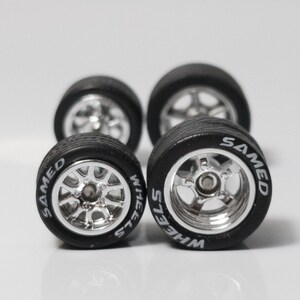 May include: Four silver chrome wheels with black tires. The tires have white lettering that reads 'WHEELS' and 'SAMED'.