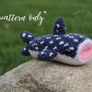 Può includere: Schema all'uncinetto per un amigurumi squalo balena. Il giocattolo di peluche è blu e bianco con una bocca rosa e occhi neri. Lo schema è disponibile per l'acquisto.