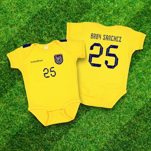 May include: Two yellow baby onesies with blue and white accents. One onesie has the text "marathon" and the number "25" printed on the front. The other onesie has the text "BABY SANCHEZ" and the number "25" printed on the back.