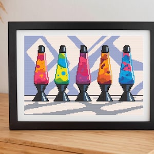 May include: A framed print displaying a pixel art design of five lava lamps. Each lamp has a black base and cap, with colourful lava in shades of orange, pink, yellow, blue, and purple. The background features a light blue and white geometric pattern.