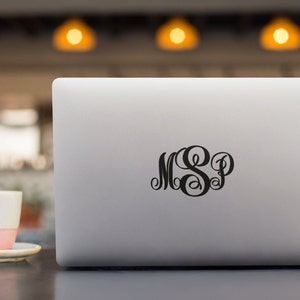 May include: A silver laptop computer with a black monogram sticker of the letters "MSP" on the lid.