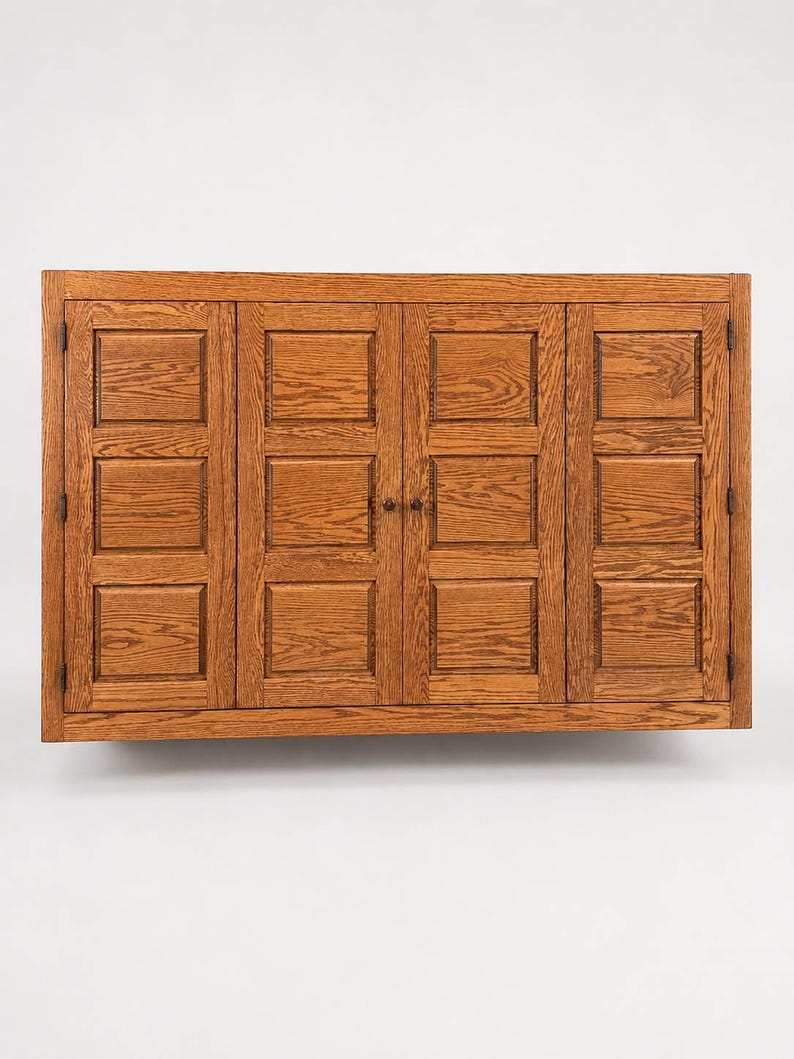 Front view of wall mounted oak TV cover cabinet with raised panel bi-fold doors in Chestnut finish.