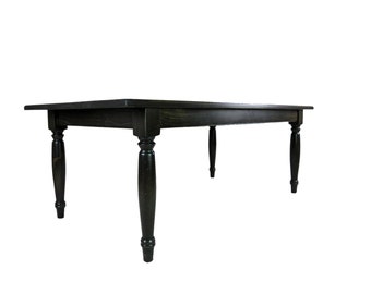 May include: A rectangular dining table with a dark black finish and visible wood grain texture. The table features four turned legs with a rounded, tapered design that support a flat, smooth tabletop surface with straight edges.