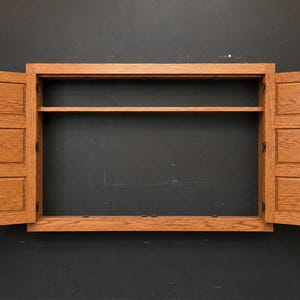Open oak TV cover cabinet showing interior shelf and open-back design for wall-mounted television installation.