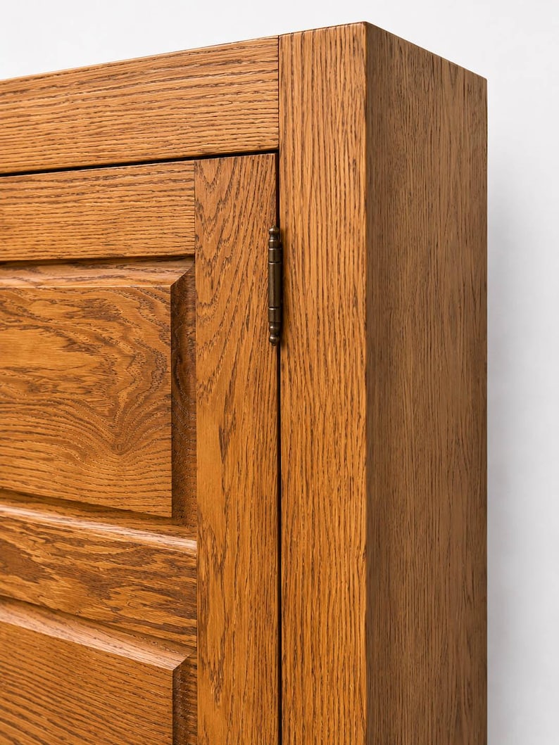 Corner detail of solid oak TV cabinet showing handcrafted joinery, frame construction, and wood grain.