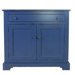 K&ouml;nnte beinhalten: Ein blauer, lackierter Holzschrank mit zwei T&uuml;ren und einer Schublade. Der Schrank hat ein schlichtes Design mit einer leicht abgenutzten Oberfl&auml;che.