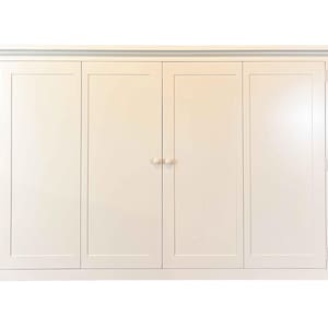 May include: A large, off-white cabinet with four doors and a decorative top molding. The cabinet doors have a recessed panel design and are fitted with small, round knobs. The cabinet is painted in a neutral color, suitable for various interior styles.