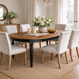 Oval farmhouse dining table shown with simple wooden chairs for scale in a neutral farmhouse dining room setting.