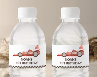 Può includere: Due bottiglie d'acqua in plastica trasparente con etichette bianche. Le etichette mostrano un'auto da corsa rossa con un numero uno bianco e un palloncino. Il testo sulle etichette recita "Noah's 1st Birthday" con un bordo a scacchi bianco e nero.