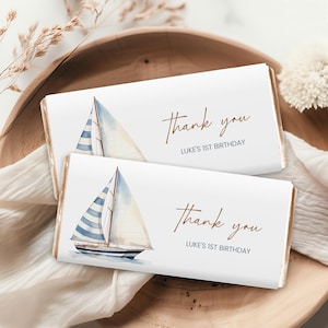 May include: Two white chocolate bar wrappers with a watercolor illustration of a sailboat with blue and white stripes. The text "Thank you" and "Luke's 1st Birthday" is printed in brown on each wrapper.