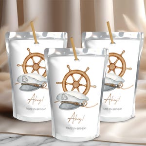 Puede incluir: Tres bolsas de jugo blancas y plateadas con un tema náutico. Cada bolsa tiene un sombrero de marinero azul y blanco, un timón marrón y el texto "Ahoy! Tom's 5th Birthday".