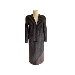 May include: A black and white striped skirt suit with a V-neck jacket.