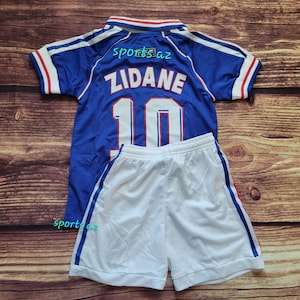 May include: A blue and white soccer jersey and shorts set. The jersey has the name "ZIDANE" and the number "10" on the back. The jersey and shorts have blue and red accents. The text "sports az" is on the jersey.