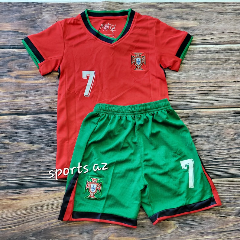 May include: Red and green soccer jersey and shorts set with the number 7 and the Portuguese national team crest. The jersey has black trim on the sleeves and collar. The shorts have black trim on the waistband and legs.