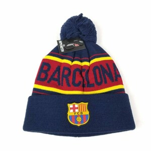May include: A blue knit beanie with a red and yellow stripe and the word "BARCELONA" in white. The beanie has a pom-pom on top and a FC Barcelona logo on the front.