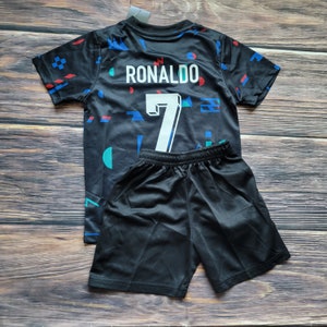 May include: Black soccer jersey with a geometric pattern and the name "RONALDO" and the number "7" on the back. The jersey is paired with black shorts.