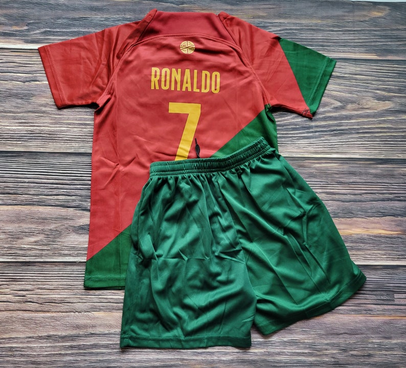 May include: Red and green soccer jersey with the name "RONALDO" and the number "7" on the back. The jersey is paired with green soccer shorts.
