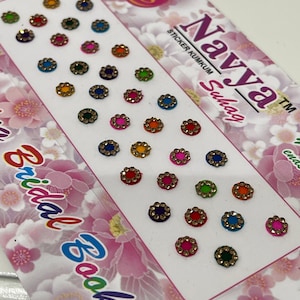 May include: A sheet of colorful, round, decorative stickers with a gold trim. The stickers are arranged in rows on a white background with the text "Navya Suhag" and "Sticker Kumkum" printed on the right side. The text "Bridal Book" is printed on the left side.