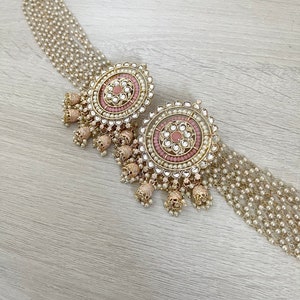 May include: A pair of large, round, gold earrings with pink and white stones and pearl accents. The earrings have a dangling design with multiple layers of pearls.
