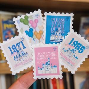 Pode incluir: Uma cole&ccedil;&atilde;o de selos postais vintage com o tema Disney. Os selos apresentam imagens ic&oacute;nicas como bal&otilde;es do Mickey Mouse, o castelo da Cinderela e texto como "1971" e "Disneyland". Os selos s&atilde;o em v&aacute;rias cores, incluindo azul, rosa e amarelo.