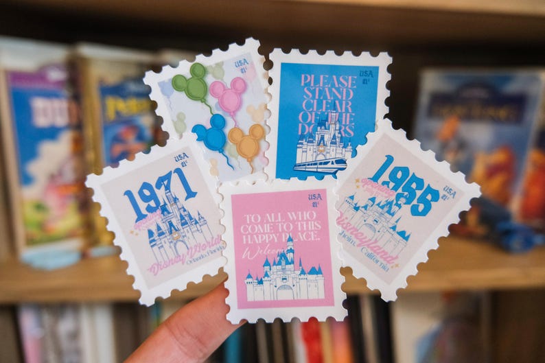 Pode incluir: Uma cole&ccedil;&atilde;o de selos postais vintage com o tema Disney. Os selos apresentam imagens ic&oacute;nicas como bal&otilde;es do Mickey Mouse, o castelo da Cinderela e texto como "1971" e "Disneyland". Os selos s&atilde;o em v&aacute;rias cores, incluindo azul, rosa e amarelo.