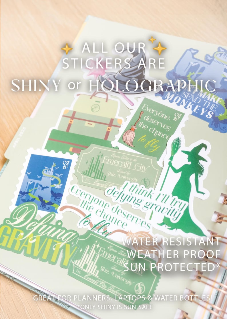 Op de afbeelding: Een verzameling glanzende en holografische stickers met Wizard of Oz-thema's. De stickers bevatten afbeeldingen van een heks, een bezem, koffers en de Emerald City. Tekst bevat "Defying Gravity" en "Everyone deserves the chance to fly."