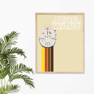 May include: A framed print with a retro-style design featuring the Millennium Falcon spaceship from Star Wars. The spaceship is white with grey details and is flying through a colourful stripe pattern of yellow, orange, red, and brown. The text "STAR WARS" is printed in white on a beige background.