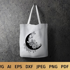 May include: A white tote bag with a black and white crescent moon design. The moon is decorated with intricate floral patterns.