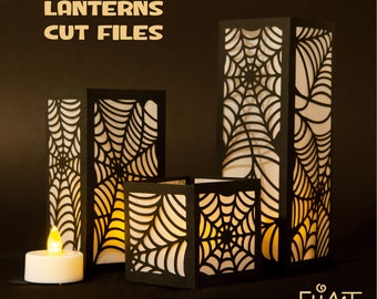 May include: Three paper lanterns with a spiderweb design. The lanterns are black with white paper inside. The lanterns are lit with candles. The image includes the text "PAPER LANTERNS CUT FILES" and "3 DESIGNS".