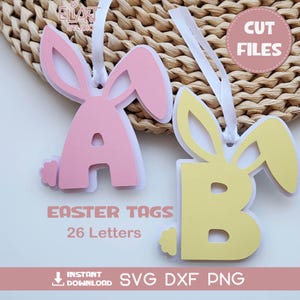 May include: Pink and yellow Easter tags shaped like bunnies, with the letters "A" and "B". The tags have white ribbon for hanging. Text on the image reads "Easter Tags 26 Letters" and "SVG DXF PNG".