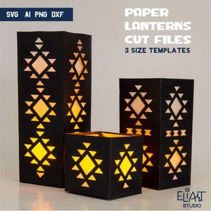 Op de afbeelding: Drie zwarte papieren lantaarns met geometrische uitsnijdingen. De lantaarns zijn van binnenuit verlicht en geven een warm gloed af. De lantaarns zijn van verschillende groottes, waarbij de grootste ongeveer 30 cm hoog is. De lantaarns zijn gelabeld met "Paper Lanterns Cut Files" en "3 Size Templates".