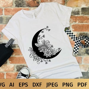 May include: A white t-shirt with a black and white design of a crescent moon with floral details.