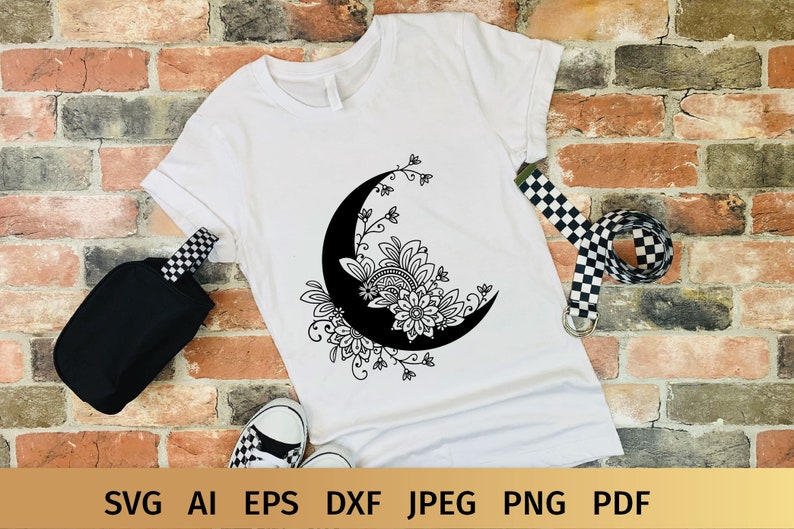 May include: A white t-shirt with a black and white design of a crescent moon with floral details.