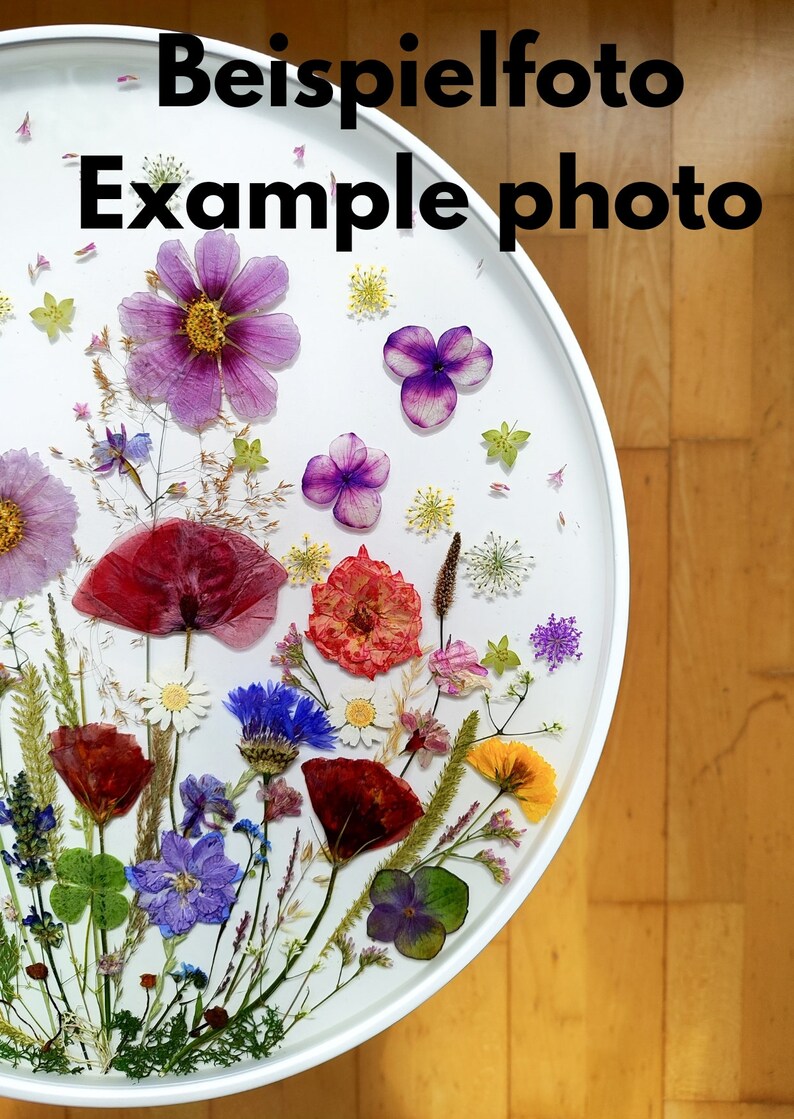 Puede incluir: Una mesa redonda blanca con una variedad de flores y hojas prensadas incrustadas en resina transparente. Las flores son de color rosa, morado, rojo, amarillo y blanco.