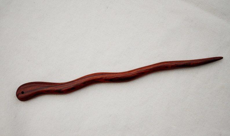 Puede incluir: Un palo de pelo largo y delgado de madera roja oscura con un mango curvo. El palo tiene un patr&oacute;n de veta de madera natural.