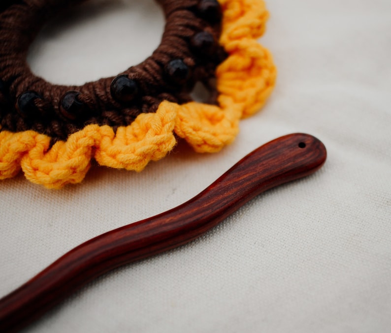 Puede incluir: Un scrunchie para el pelo de color marr&oacute;n y amarillo tejido a crochet con cuentas marrones y un palo para el pelo de madera oscura.