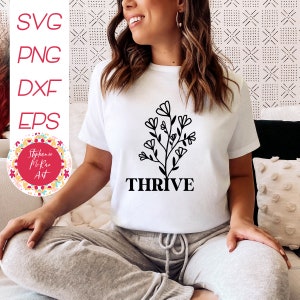 May include: White t-shirt with a black floral design and the word "THRIVE" printed below it.