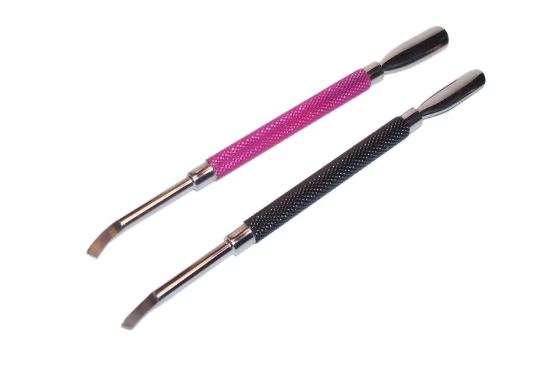 Pode incluir: Dois empurradores de cut&iacute;culas para unhas com pontas de metal. Um tem uma al&ccedil;a rosa com um padr&atilde;o de diamante texturizado e o outro tem uma al&ccedil;a preta com um padr&atilde;o de diamante texturizado.