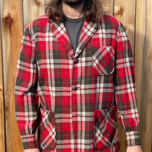 Könnte beinhalten: Ein roter, brauner und weißer karierter Blazer mit zwei aufgesetzten Taschen und einem Knopfverschluss.