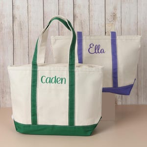 Personalized canvas tote bag with embroidered name, contrasting trim and zip-top closure, designed for travel, everyday use and personalized gifts for her.