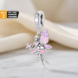 Puede incluir: Un charm de plata con un diseño de hada. El hada tiene alas rosas y moradas y un vestido rosa. El charm tiene un lazo con detalles en forma de estrella y el texto "S925". El charm está suspendido de un lazo.