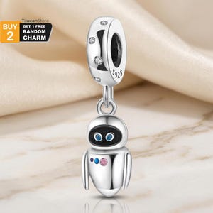 May include: A silver charm with a robot design. The charm has a round top with clear stones and the text "S925". The robot has a black face with blue eyes and a pink and blue gem on its body. The charm is suspended from a ring.