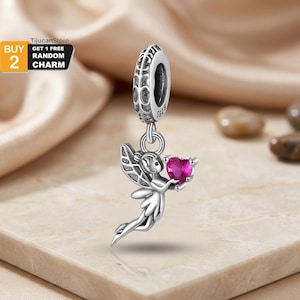 Puede incluir: Un charm de plata que representa un hada sosteniendo una gema en forma de corazón de color magenta. El charm tiene alas detalladas y ropa fluida. La parte superior del charm tiene un patrón decorativo y el texto "5925".