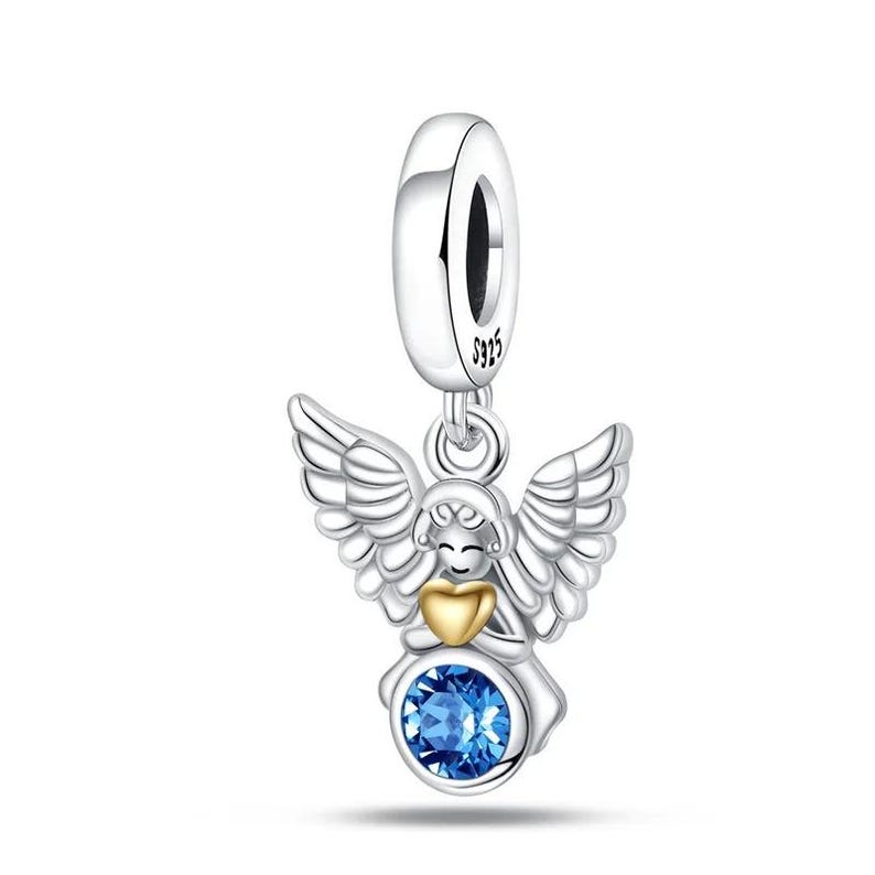 May include: A silver charm with an angel design. The angel has detailed wings, a gold heart, and a blue gemstone. The charm is suspended from a silver loop, marked with "S925".