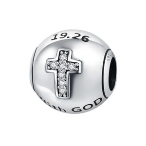 May include: A silver charm with a cross design. The cross is adorned with clear gemstones. The charm has the text "19.26" and "with GOD" engraved on it. The charm is round and has a black accent.