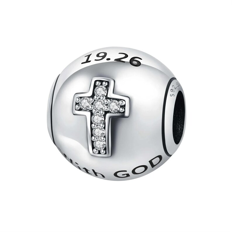 May include: A silver charm with a cross design. The cross is adorned with clear gemstones. The charm has the text "19.26" and "with GOD" engraved on it. The charm is round and has a black accent.