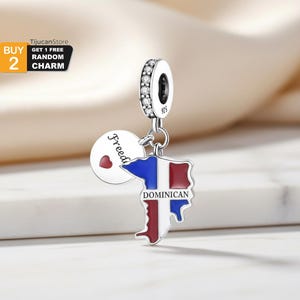 May include: A silver charm with a Dominican Republic flag design. The charm features a blue, white, and red flag shape with the word "DOMINICAN" below. A round charm with a red heart and the word "Freedom" is also included.