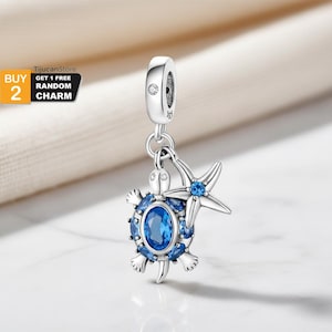 Könnte beinhalten: Ein silberner Charm-Anhänger mit einem Schildkröten- und Seestern-Design mit blauen Edelsteinakzenten. Die Schildkröte hat einen ovalen blauen Edelstein in der Mitte, umgeben von kleineren blauen Edelsteinen. Der Seestern hat einen einzelnen blauen Edelstein.