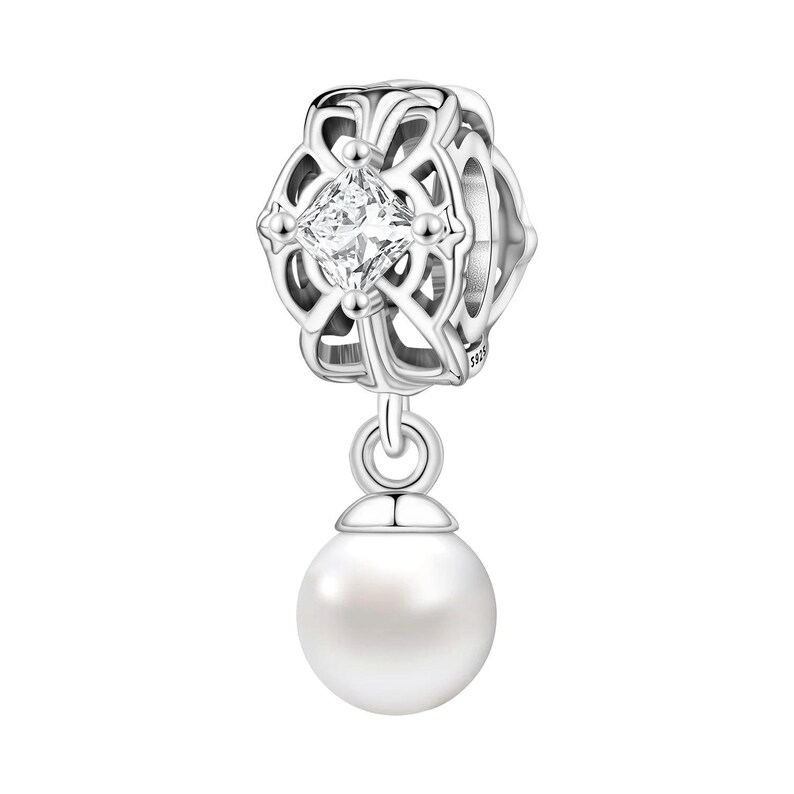 May include: A silver charm with a square, clear gemstone at the center of an openwork design. A white pearl dangles below. The charm is likely for a bracelet or necklace, and is a jewelry item.