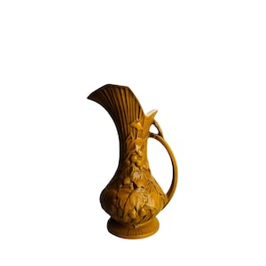 May include: A brown ceramic pitcher with a wide mouth and a handle. The pitcher is decorated with a raised design of leaves and grapes.